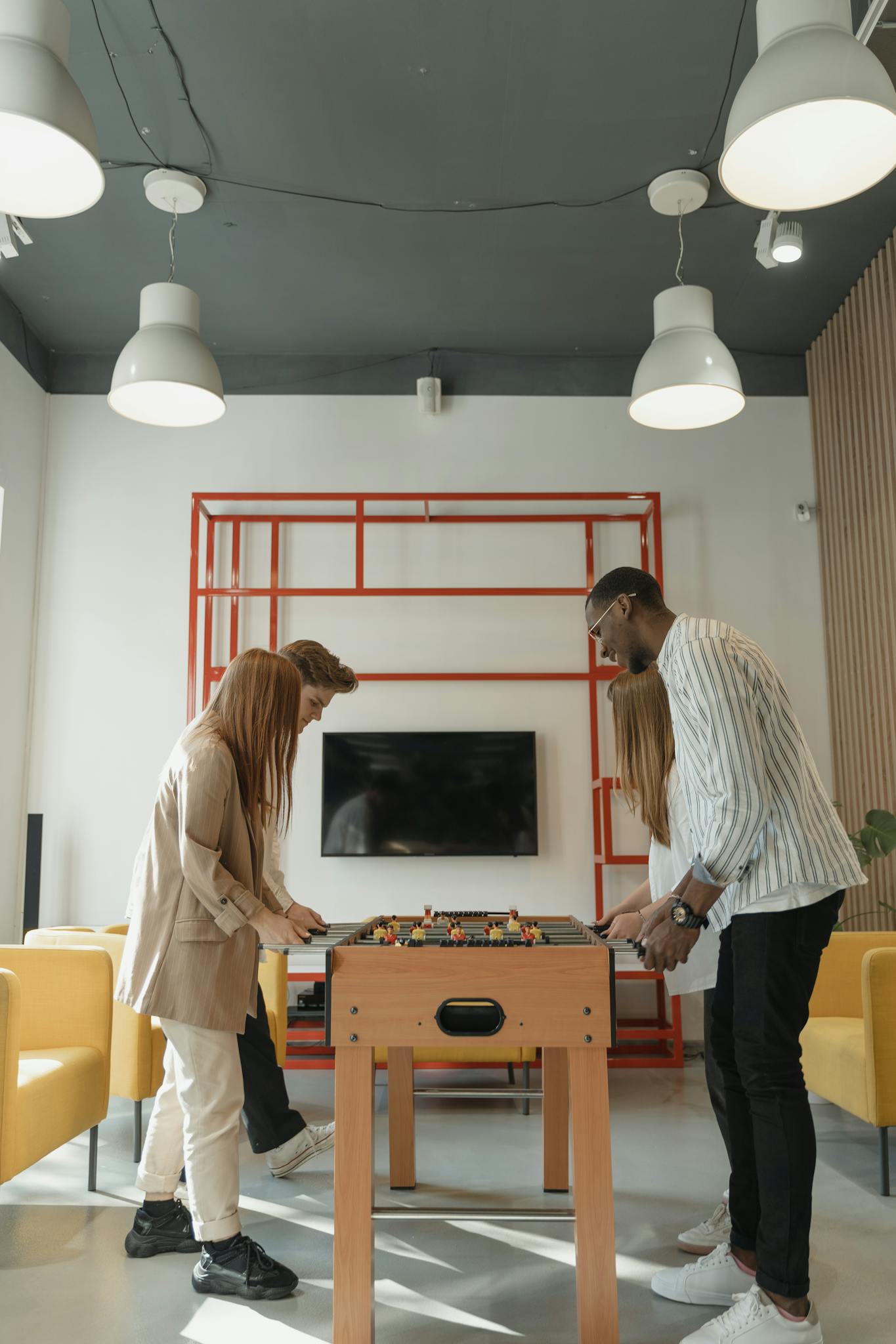 Energetic adults playing table football indoors, showcasing fun and teamwork.